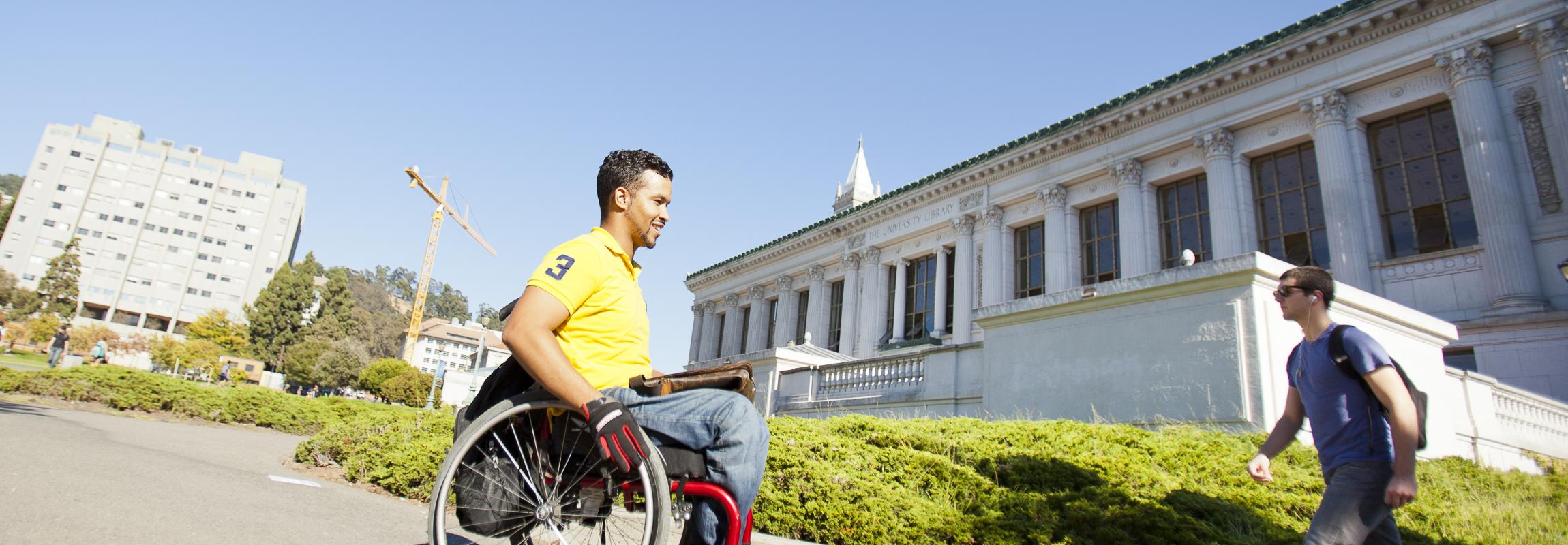 Photo of a student making his way across campus in a wheelchair