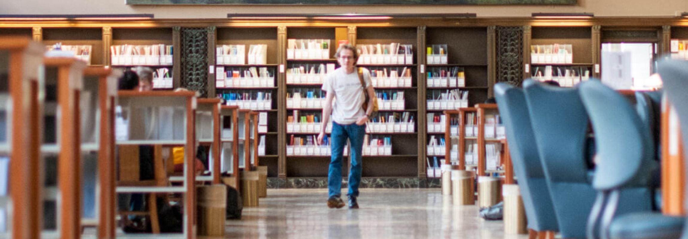 Photo of a student walking through a library